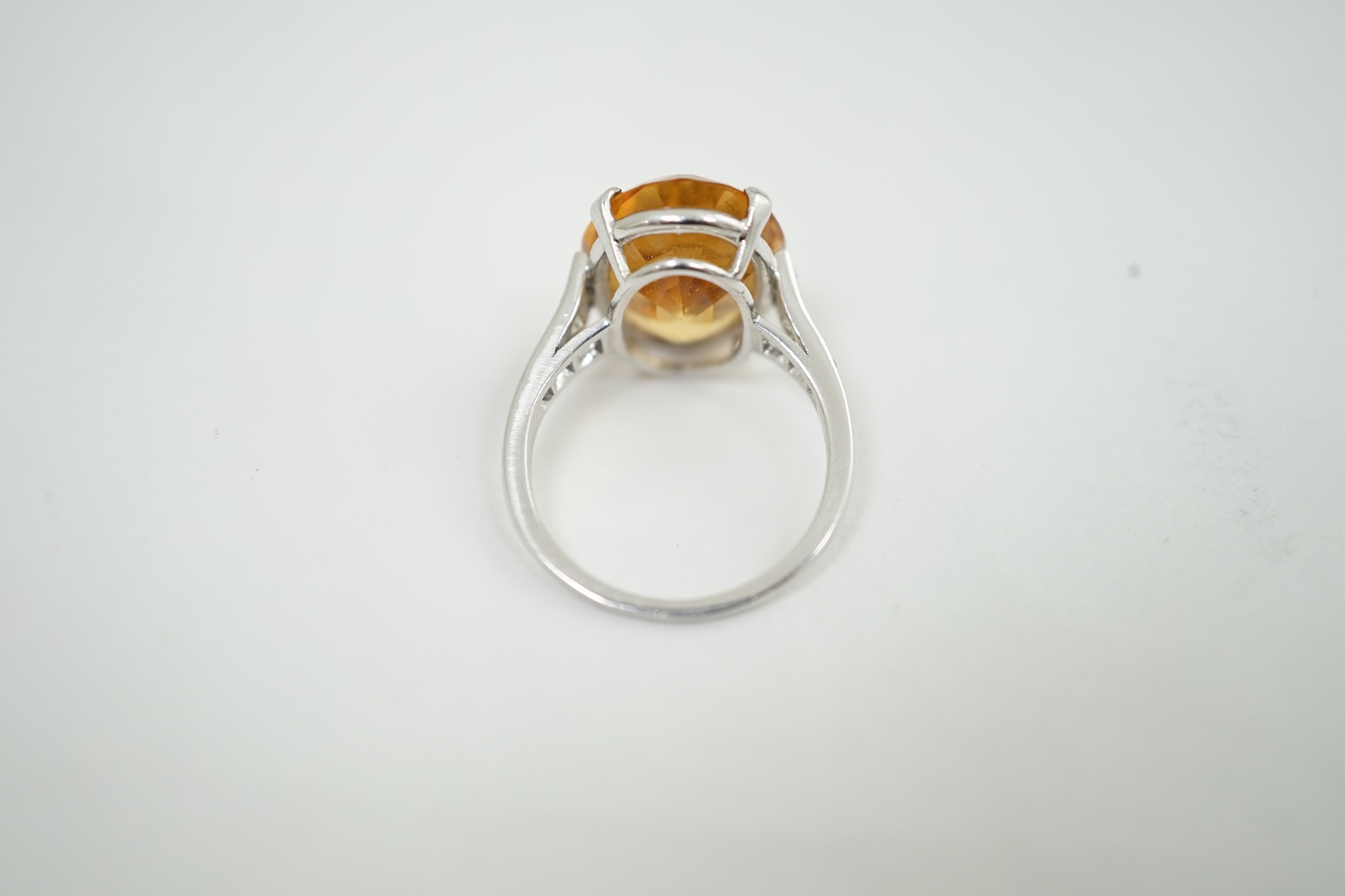 A 1940's platinum? and single stone oval cut imperial? topaz set dress ring, with ten stone graduated round cut diamond set shoulders